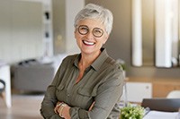 Senior woman with glasses smiling with arms folded