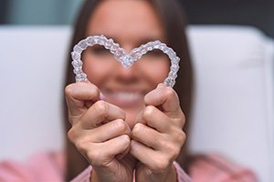 Patient holding up two Invisalign aligners in Collierville to make a heart shape