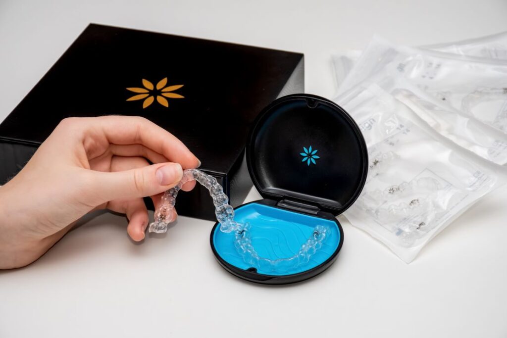 A woman's hand putting an Invisalign aligner into an aligner case.